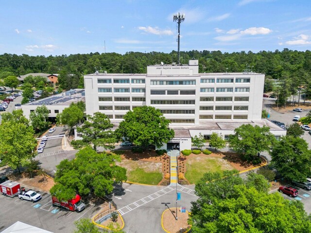 view of property with uncovered parking and a forest view