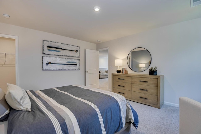 bedroom with a walk in closet, light carpet, and a closet