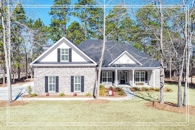 view of front facade featuring covered porch, roof with shingles, a front lawn, and brick siding