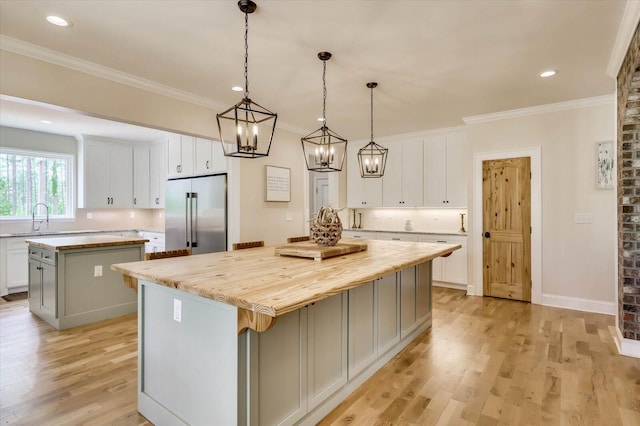 kitchen with a center island, white cabinetry, sink, and high end refrigerator