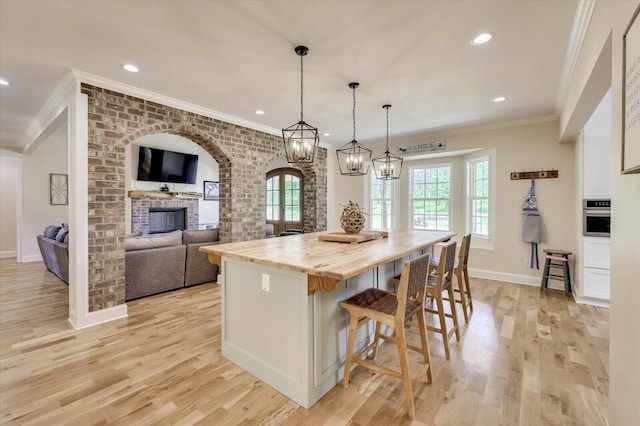 kitchen with stainless steel oven, decorative light fixtures, a center island, butcher block countertops, and a breakfast bar area