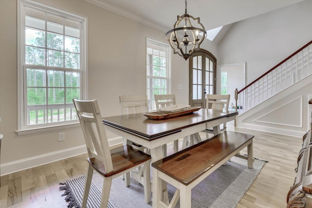 dining space featuring plenty of natural light, ornamental molding, light hardwood / wood-style flooring, and an inviting chandelier