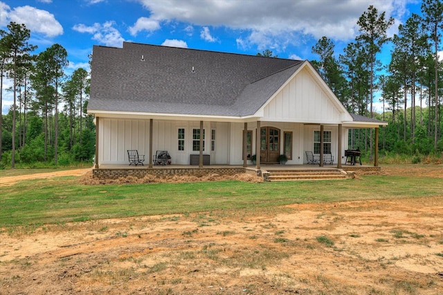 rear view of property with covered porch and a yard