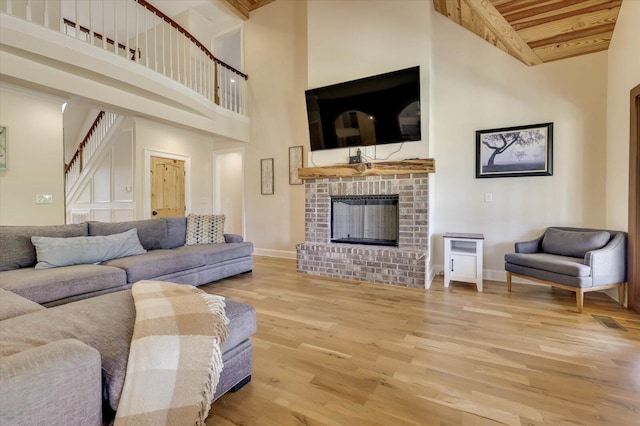 living room with wood-type flooring, wood ceiling, high vaulted ceiling, and a brick fireplace