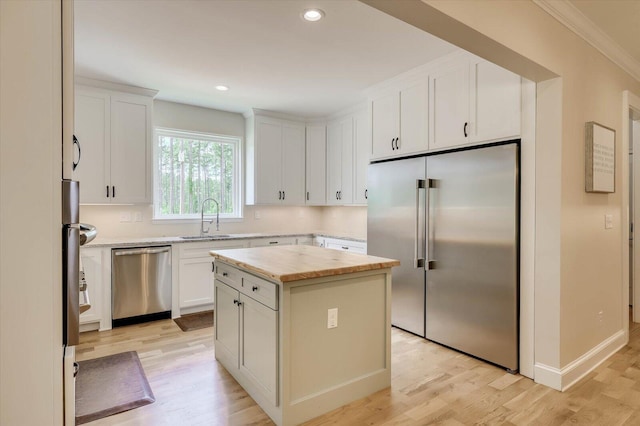 kitchen with white cabinets, appliances with stainless steel finishes, a center island, and sink