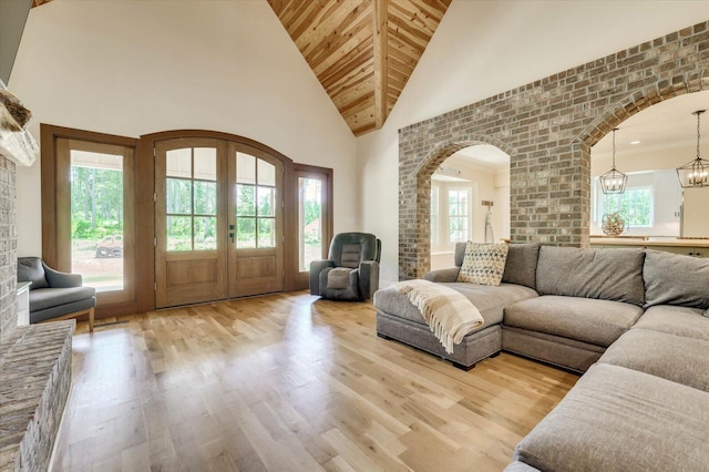 living room with french doors, high vaulted ceiling, a notable chandelier, and light wood-type flooring