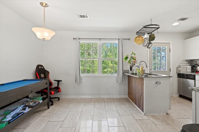 kitchen featuring kitchen peninsula, stainless steel dishwasher, sink, decorative light fixtures, and pool table