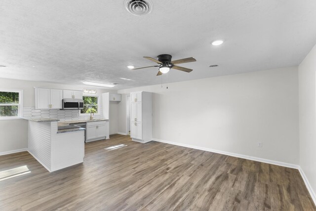319 Indian Trl, Augusta, GA 30907 - kitchen with stainless steel microwave, baseboards, white cabinetry, a peninsula, and wood finished floors