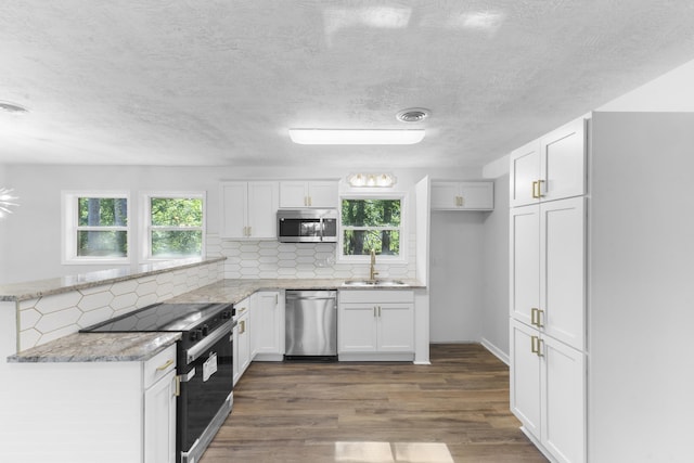 319 Indian Trl, Augusta, GA 30907 - kitchen with appliances with stainless steel finishes, a sink, a peninsula, white cabinetry, and backsplash