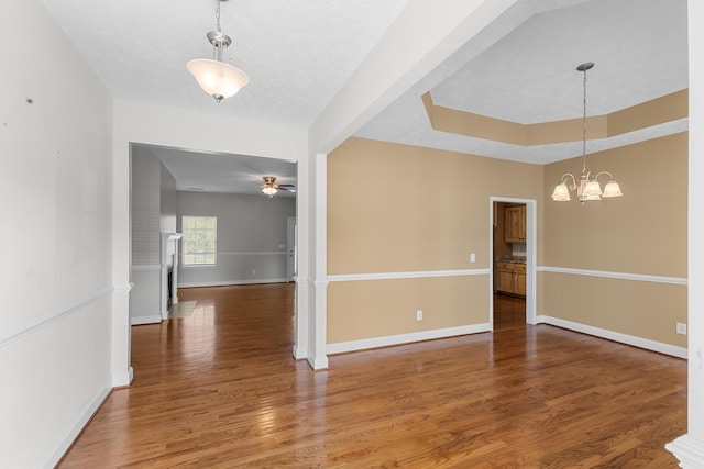 unfurnished dining area with light wood-type flooring, a chandelier, baseboards, and ceiling fan