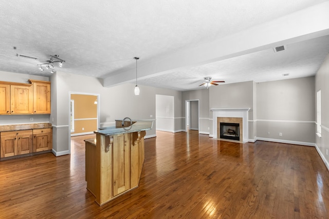 kitchen with ceiling fan, dark wood-style floors, a tiled fireplace, decorative light fixtures, and a textured ceiling