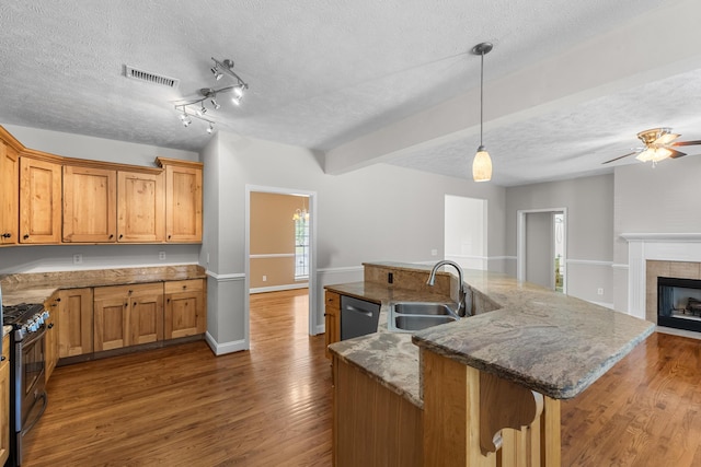 kitchen with a sink, gas range, dishwasher, dark wood finished floors, and a textured ceiling