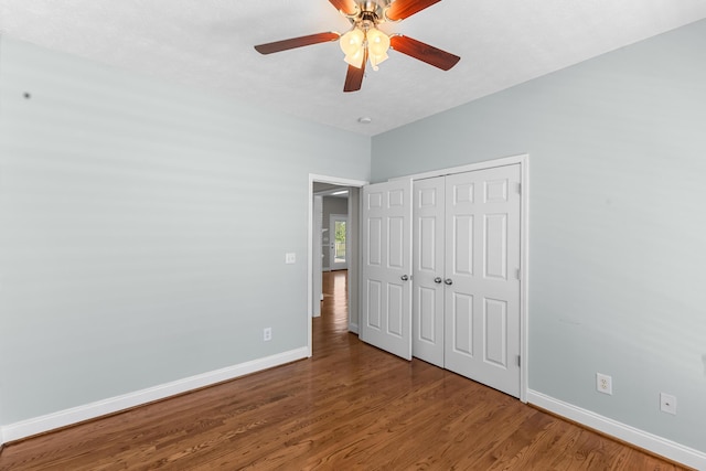 unfurnished bedroom with baseboards, wood finished floors, a closet, and ceiling fan