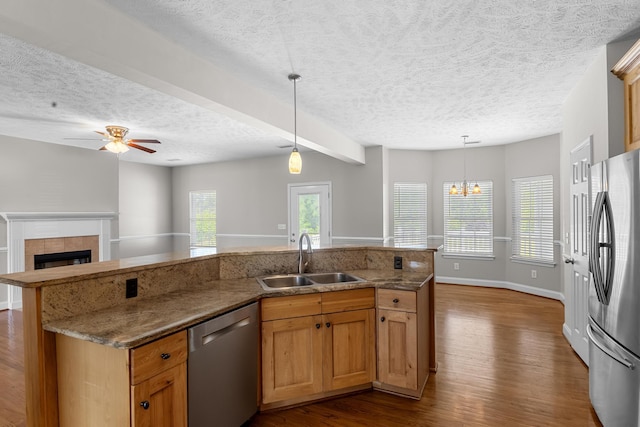 kitchen with stainless steel appliances, a sink, a textured ceiling, dark wood-style floors, and open floor plan