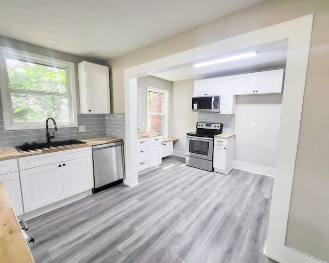 kitchen featuring wood counters, stainless steel appliances, white cabinets, and sink