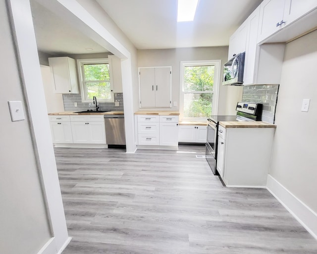 kitchen featuring butcher block countertops, white cabinetry, appliances with stainless steel finishes, and tasteful backsplash