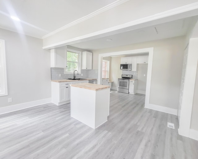 kitchen featuring sink, white cabinetry, light hardwood / wood-style floors, butcher block counters, and stainless steel appliances