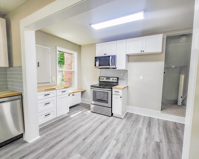 kitchen with wooden counters, appliances with stainless steel finishes, backsplash, light hardwood / wood-style floors, and white cabinetry