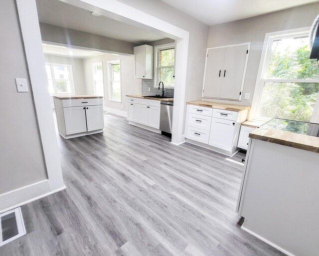 kitchen featuring backsplash, white cabinets, sink, stainless steel dishwasher, and a wealth of natural light