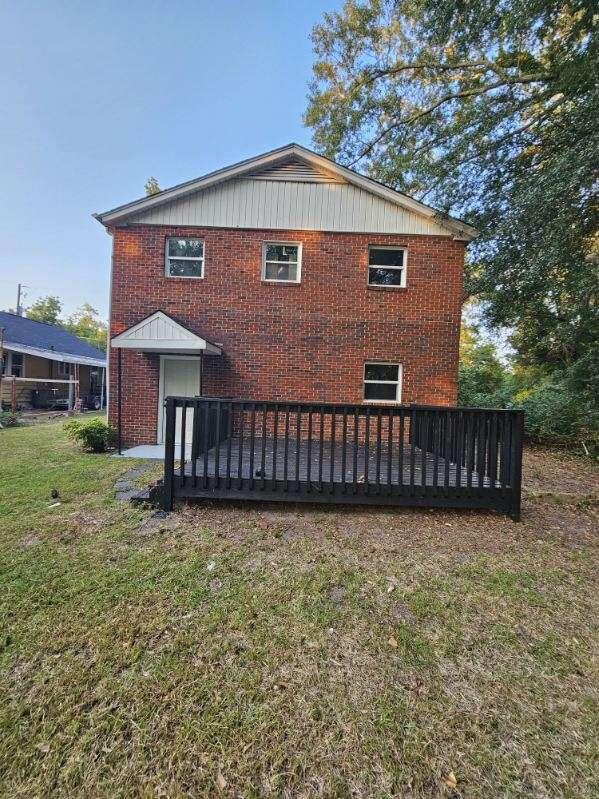 rear view of house featuring a lawn and a wooden deck