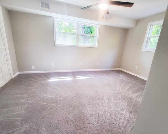 carpeted spare room featuring plenty of natural light and ceiling fan