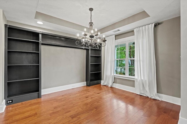 459 Sebastian Dr, Grovetown, GA 30813 - unfurnished dining area with wood finished floors, a chandelier, built in shelves, and a raised ceiling
