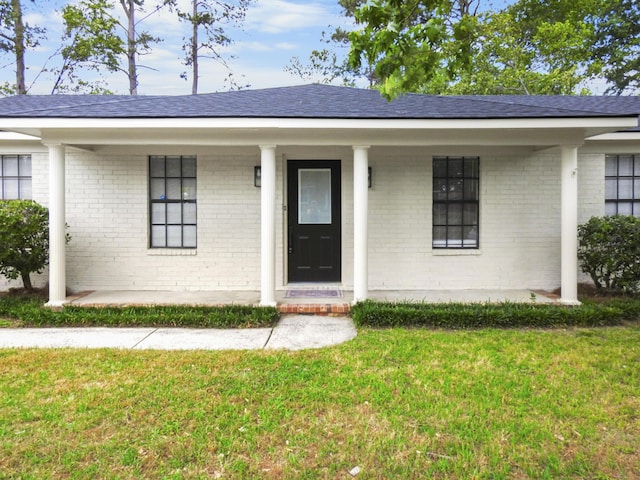 view of front of property with a front lawn, covered porch, and brick siding