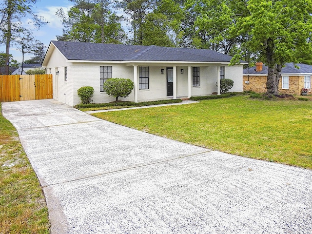 ranch-style home featuring brick siding, fence, a shingled roof, driveway, and a front yard