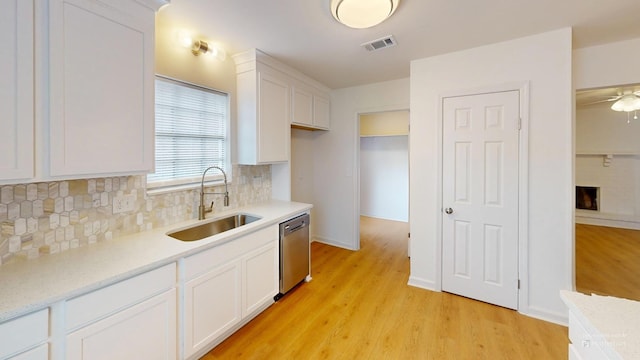 kitchen with a sink, tasteful backsplash, visible vents, white cabinetry, and stainless steel dishwasher