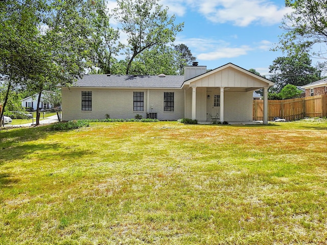 rear view of house featuring a lawn, a chimney, and fence