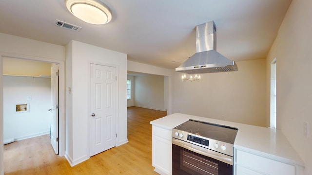 kitchen featuring electric stove, island range hood, light wood-style floors, light countertops, and visible vents