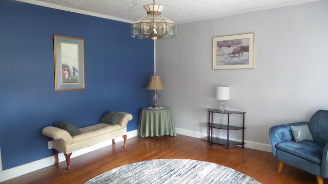 sitting room with ornamental molding, dark hardwood / wood-style flooring, a textured ceiling, and a notable chandelier