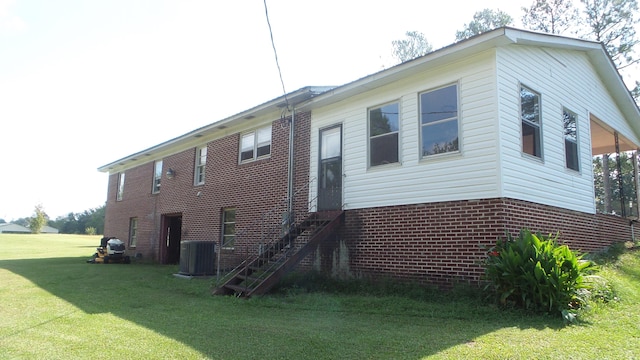 view of side of property featuring a yard and central AC