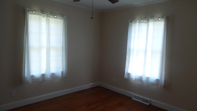 unfurnished room featuring ceiling fan, dark wood-type flooring, and a healthy amount of sunlight