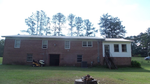 rear view of property with central AC and a lawn