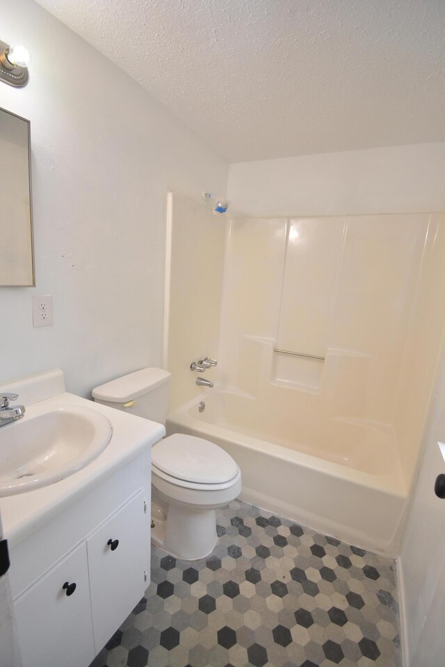 full bathroom with shower / tub combination, vanity, a textured ceiling, and toilet