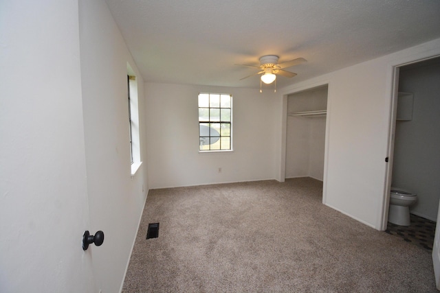 unfurnished bedroom with carpet floors, a closet, ceiling fan, and connected bathroom