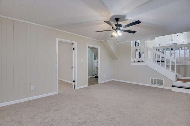 unfurnished living room with a textured ceiling, ceiling fan, light colored carpet, and crown molding