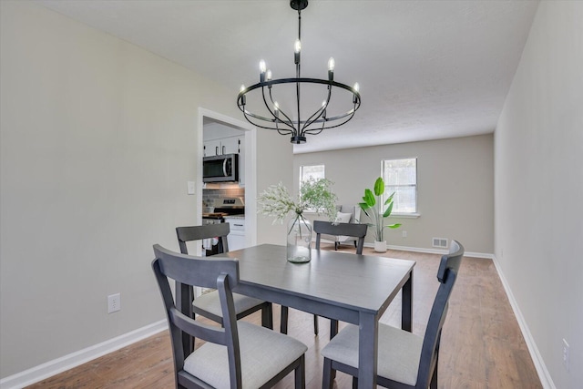 dining area with hardwood / wood-style flooring and an inviting chandelier