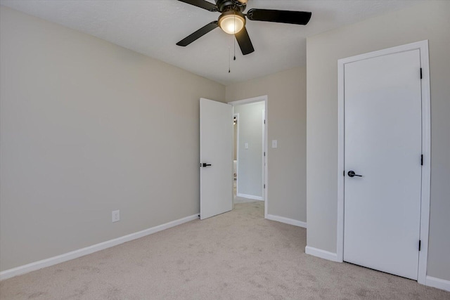 unfurnished bedroom featuring ceiling fan, light carpet, and a closet