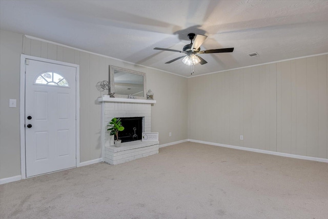 unfurnished living room featuring ceiling fan, crown molding, light carpet, and a brick fireplace