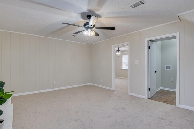 carpeted empty room featuring a textured ceiling, ceiling fan, and ornamental molding