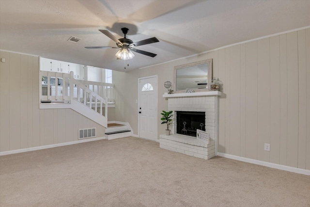 unfurnished living room with light carpet, a brick fireplace, a textured ceiling, ceiling fan, and wooden walls