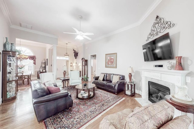 living room with ceiling fan, light hardwood / wood-style flooring, a high end fireplace, and crown molding