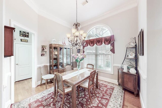 dining room featuring crown molding, light hardwood / wood-style flooring, and a chandelier