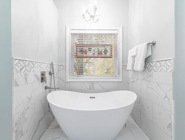 bathroom with a washtub, tile walls, and a notable chandelier