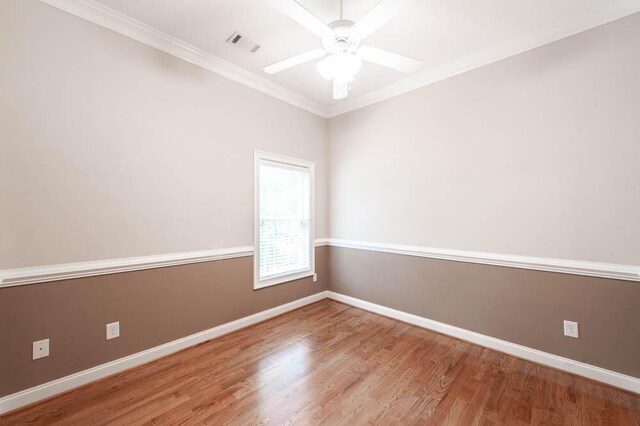 unfurnished room with a ceiling fan, baseboards, wood finished floors, visible vents, and ornamental molding