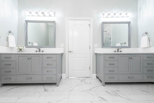 bathroom featuring a sink, baseboards, two vanities, and marble finish floor