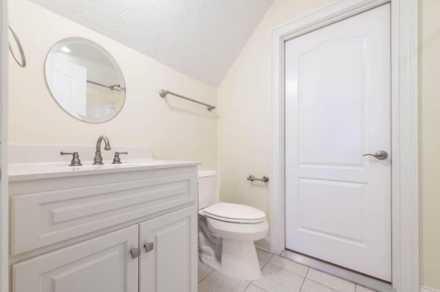 bathroom featuring vanity, toilet, tile patterned floors, a textured ceiling, and lofted ceiling