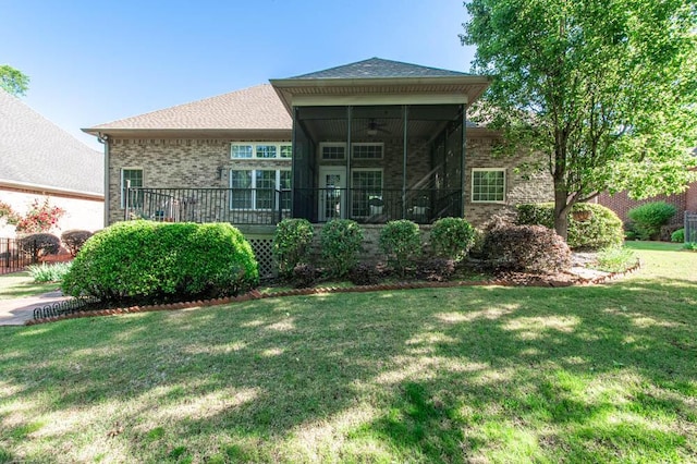 view of front of property featuring brick siding, a ceiling fan, a sunroom, and a front lawn